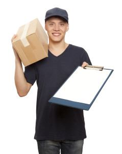 young smiling same day courier man with box on shoulder and holding clipboarc